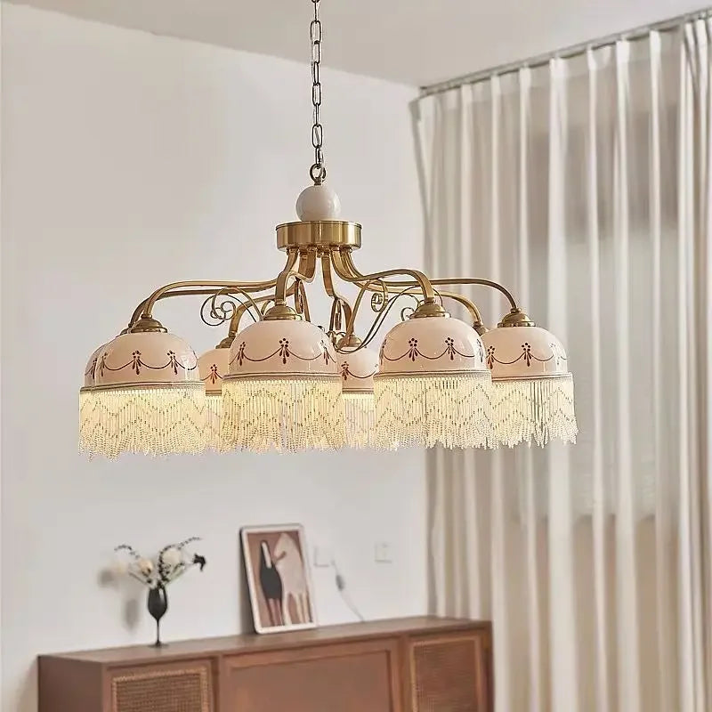 Gold multi-head pendant light with white ceramic shades, brown floral accents, tassel fringe on chain