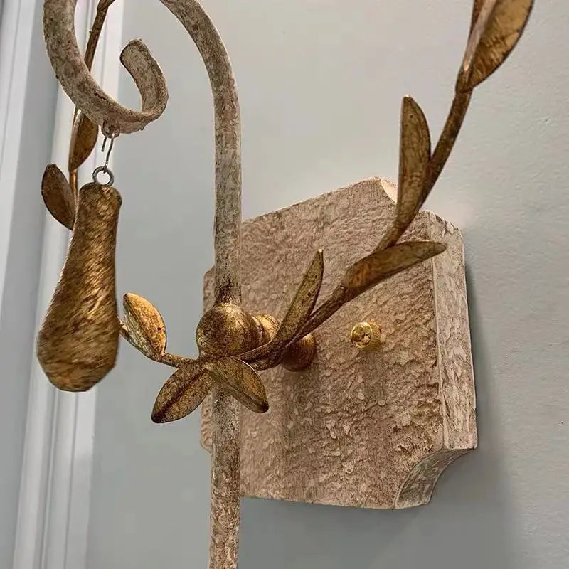 Close-up of gold leaf details and textured grey metal wall sconce backplate