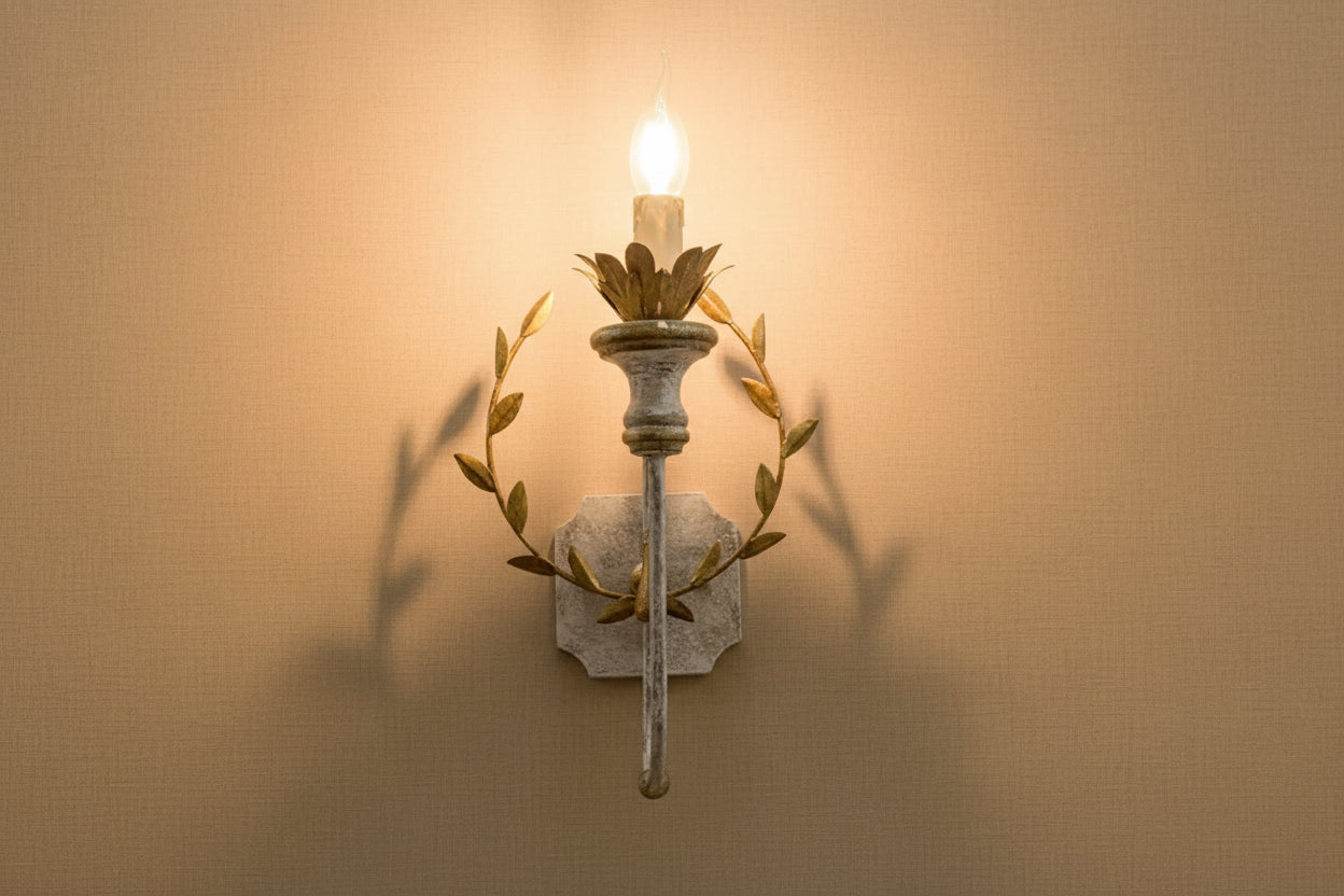 Gold and grey iron wall sconce with lit LED bulb and leaf wreath arms