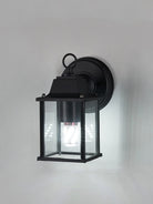 Black outdoor wall lantern light with clear glass and warm glowing bulb