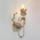 Dark iron wall sconce with candle-style LED bulb and gold leaf scroll arms