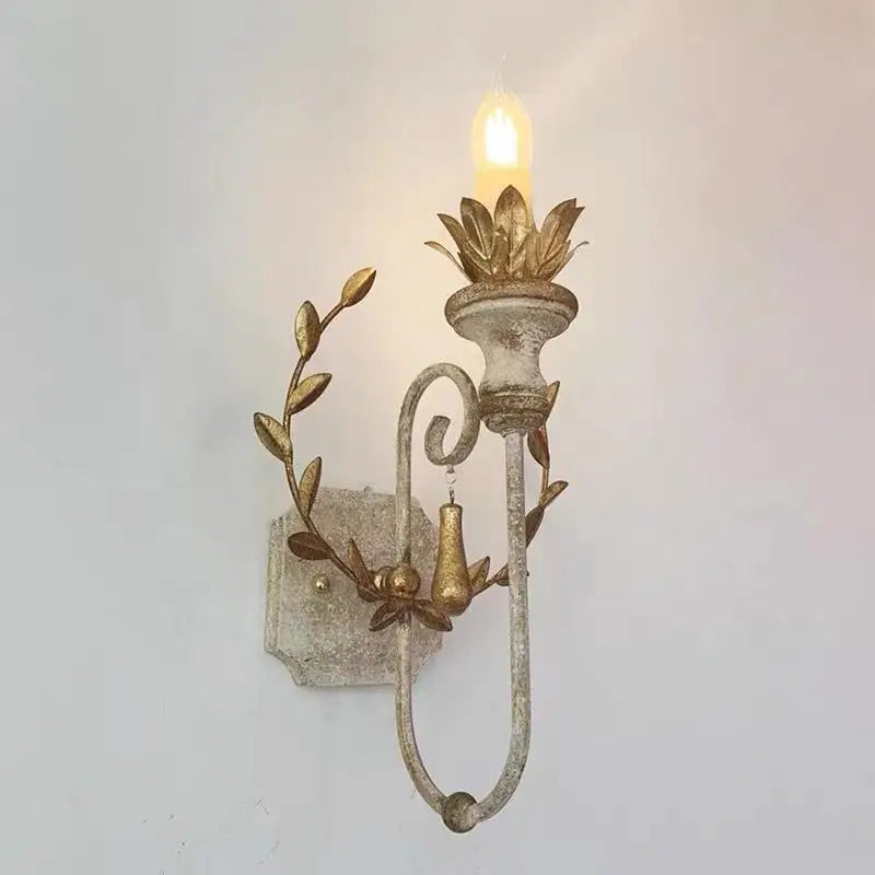 Dark iron wall sconce with candle-style LED bulb and gold leaf scroll arms