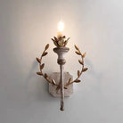 Grey metal wall sconce with warm LED flame bulb and circular gold leaf accents
