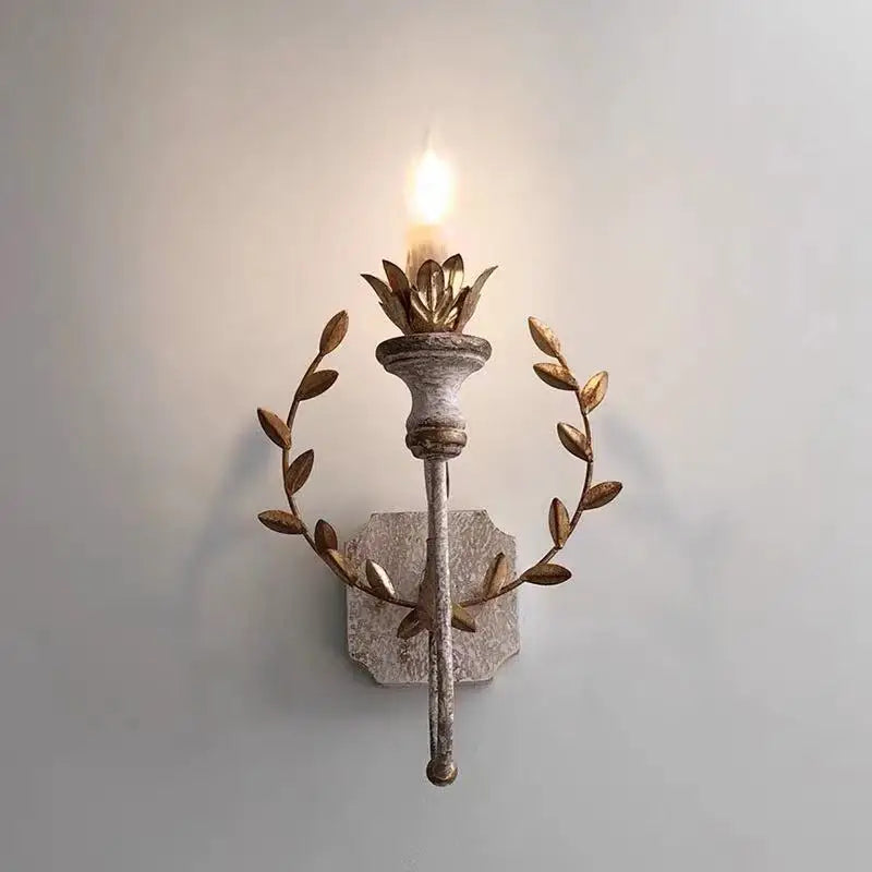 Grey metal wall sconce with warm LED flame bulb and circular gold leaf accents